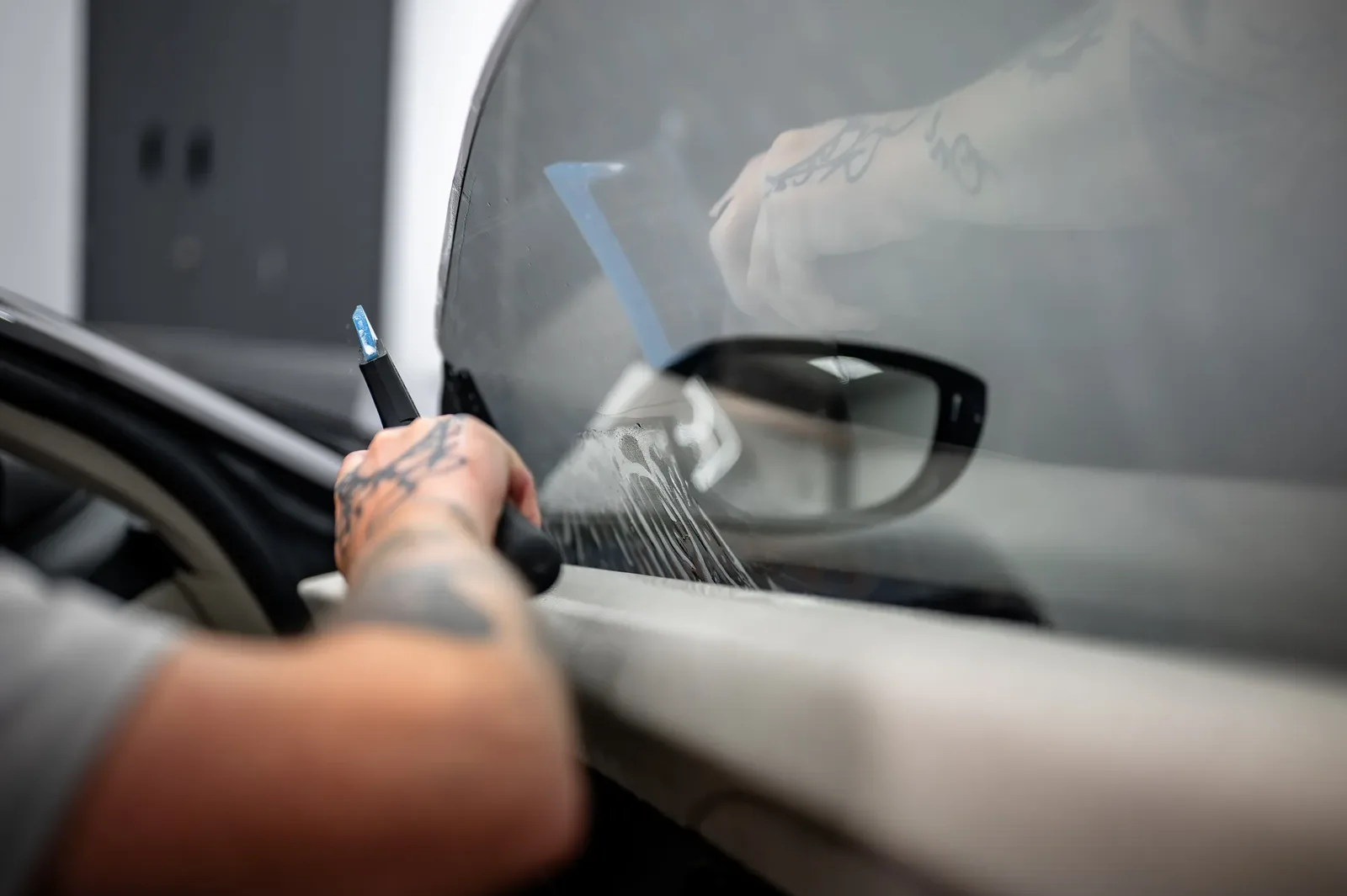 Tiger Tint & Wrap installer applying window tint film to wet glass in the Christchurch workshop