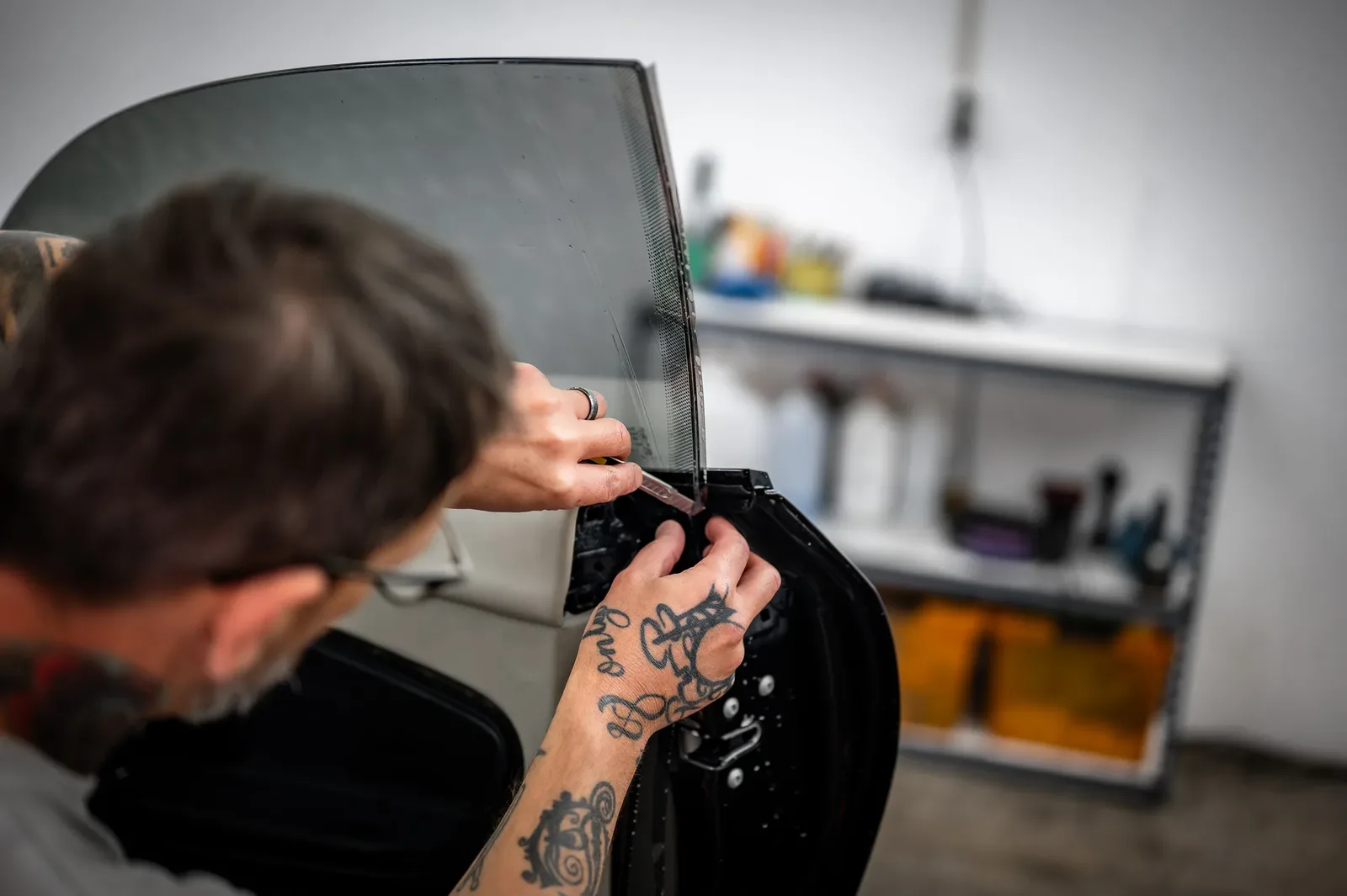 Window tint film being trimmed neatly around the door mirror on a car in Christchurch